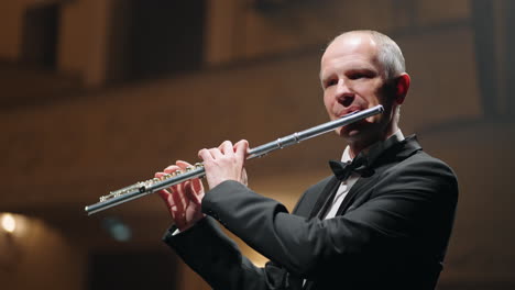 portrait-of-aged-man-with-flute-on-scene-of-old-music-hall-or-opera-house-talented-musician-is-performing-party