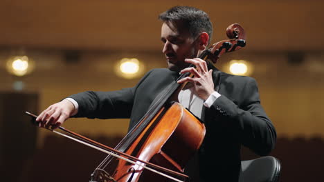 musician-in-black-suit-is-playing-cello-on-scene-of-opera-house-symphonic-orchestra-in-philharmonic-hall