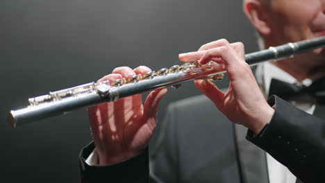 musician-is-playing-flute-in-opera-house-or-modern-music-hall-closeup-of-male-hands-with-flute