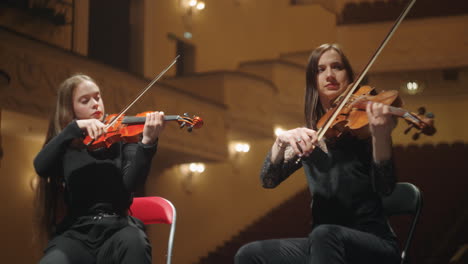 Violinistinnen-Spielen-Musik-Auf-Der-Bühne-Des-Opernhauses,-Zwei-Professionelle-Musiker-In-Der-Philharmonie
