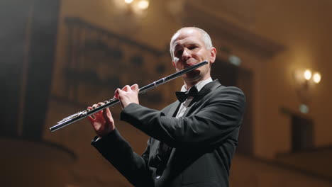 flutist-is-playing-flute-portrait-of-musician-in-concert-hall-of-philharmonic-brass-band-or-symphonic-orchestra