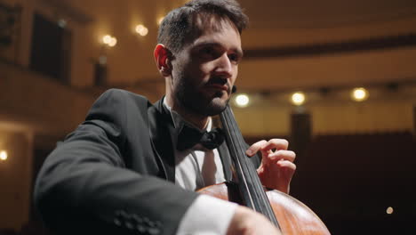 handsome-man-is-playing-cello-on-scene-of-old-opera-house-closeup-portrait-of-cellist-in-philharmonic-hall