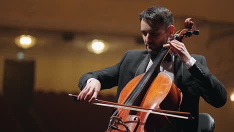 Talentierter-Cellist-Im-Schwarzen-Anzug-Spielt-Cello-Auf-Der-Bühne-Der-Opernhausprobe-Des-Symphonieorchesters