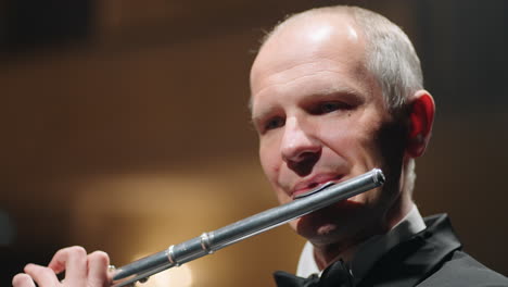portrait-of-aged-flutist-in-opera-house-closeup-view-of-male-face-with-flute-classic-music-concert