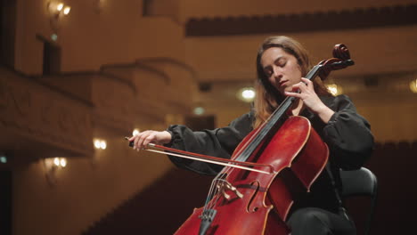 emotional-woman-is-playing-violoncello-in-music-hall-female-violoncellist-on-scene