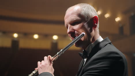 man-is-playing-flute-on-scene-of-opera-house-or-philharmonic-hall-closeup-portrait-of-talented-flutist
