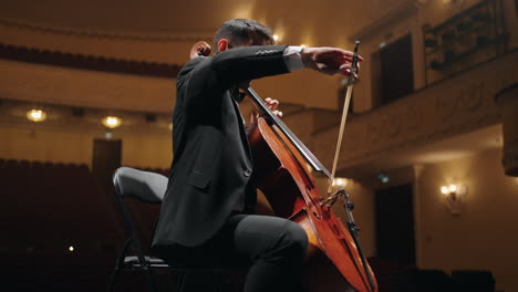 rehearsal-of-symphonic-orchestra-in-philharmonic-hall-cellist-in-black-suit-is-playing-cello-on-scene