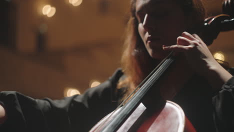 portrait-of-beautiful-emotional-female-violoncellist-on-scene-of-opera-house-woman-is-playing-cello
