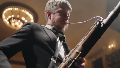 talented-musician-with-traditional-wind-instrument-on-scene-man-is-playing-bassoon-blowing-air