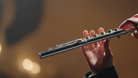 symphonic-orchestra-concert-closeup-of-flute-in-hands-of-flutist-old-opera-house-or-modern-music-hall