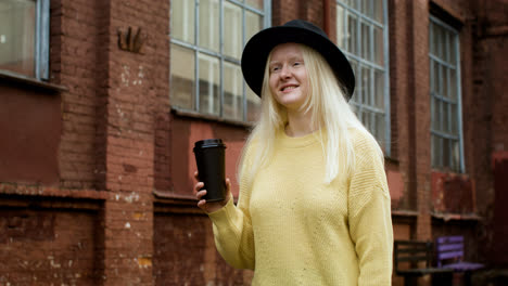 Woman-with-black-hat-holding-coffee-cup-outdoors