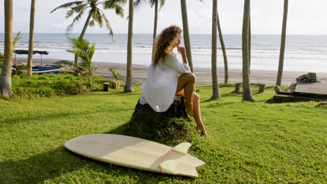 Woman-sitting-next-to-surfboard