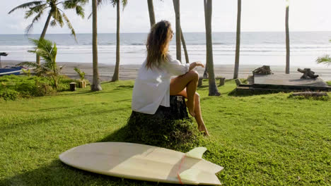 Woman-sitting-next-to-surfboard