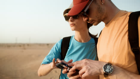 Paar-Benutzt-Smartphone-In-Der-Wüste