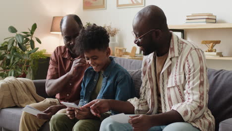 Black-men-and-boy-looking-at-pictures-in-the-living-room