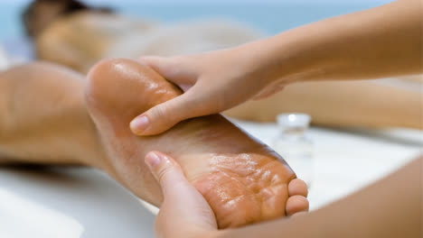 Masseuse-giving-feet-massage-to-man