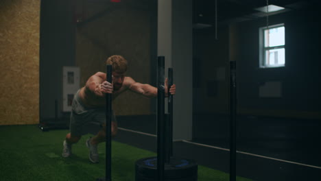 Muscular-man-pushing-sled-at-gym-during-exercise-slow-motion