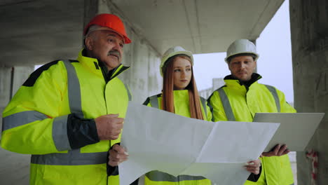 Ingenieros-Civiles-Masculinos-Y-Femeninos-Están-Inspeccionando-El-Plan-De-Construcción-Del-Arquitecto-E-Inspector-Capataz-Del-Edificio