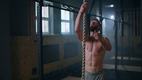 a-strong-pumped-up-man-in-the-gym-climbs-the-rope-up-and-gets-to-the-top