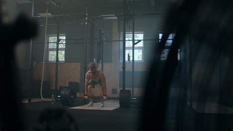 Wide-shot-of-young-Caucasian-extreme-weightlifting-athlete-man-working-out-with-heavy-barbell-in-large-hardcore-gym-hall.