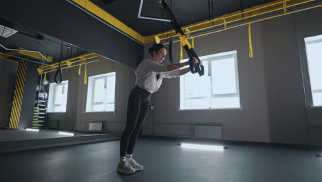 Doing-TRX-exercises.-Young-athletic-woman-in-sports-clothing-training-legs-with-trx-fitness-straps-in-the-gym.-exercise-where-stabilizing-muscles-trained-and-the-whole-body-is-working-truly-functional