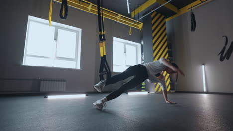 Doing-TRX-exercises.-Young-athletic-woman-in-sports-clothing-training-legs-with-trx-fitness-straps-in-the-gym.-exercise-where-stabilizing-muscles-trained-and-the-whole-body-is-working-truly-functional