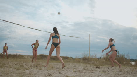 Las-Mujeres-Juegan-Voleibol-De-Playa-En-Las-Vacaciones-De-Verano,-Tomas-En-Cámara-Lenta-De-Atletas-Que-Saltan-Y-Corren-En-Una-Cancha-De-Arena