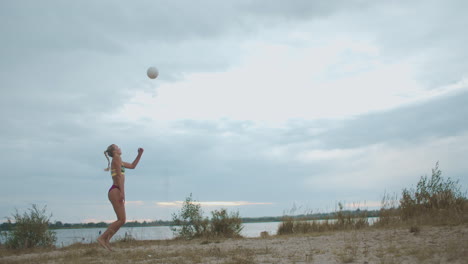 La-Mujer-Jugadora-De-Voleibol-De-Playa-Está-Entrenando-Un-Servicio-En-La-Cancha-En-La-Naturaleza,-Cámara-Lenta,-Tiro-Largo