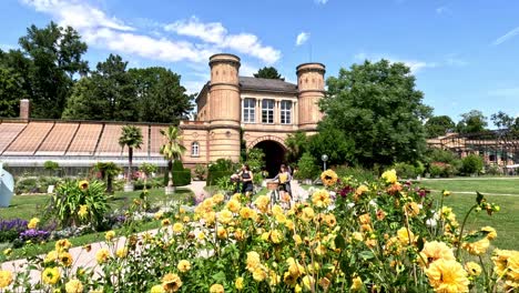 People-Walking-in-Front-of-the-Beautiful-Baroque-Tower-Gate-Building-and-Enjoying-a-Sunny-Day-at-the-Botanical-Garden-in-Karlsruhe