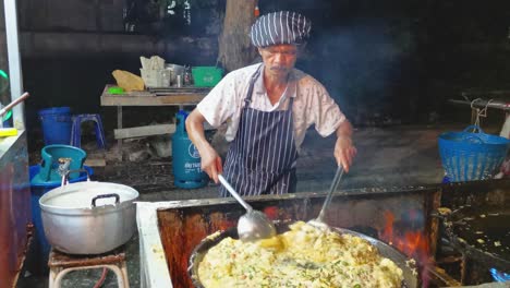 Freshly-Fried-Mussel-Pancakes-Cooked-by-an-Entertaining-Chef-Dancing-While-Cooking-Street-Food-in-Ayutthaya,-Thailand