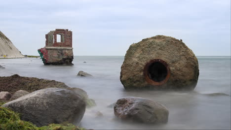 Sea-Tides-Timelapse-by-Ruins-of-Old-Gauge-Tower-on-Shore-Bellow-Cape-Arkona-Lighthouse-Cliff-at-Baltic-Sea-on-Rugen-Island,-Germany