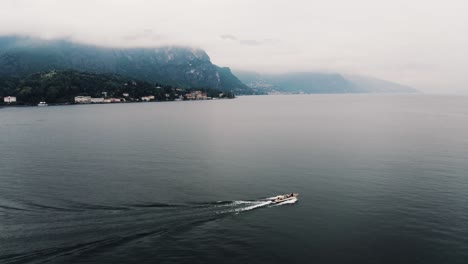 Aerial-view-of-a-private-boat-cruising-through-Lake-Como-in-Italy's-remote-mountains