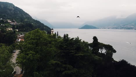 Drone-shot-flying-over-trees-along-Lake-Como-to-reveal-the-town-of-Bellagio-in-Italy