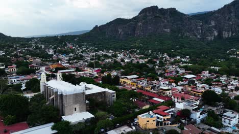 Aerial-tracking-shot-in-front-of-the-Parroquia-Nuestra-Señora-de-la-Natividad-in-Tepoztlan,-Morelos,-cloudy-Mexico