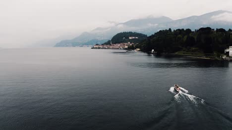 Drone-shot-of-a-boat-passing-through-a-calm-Lake-Como-during-the-middle-of-the-day