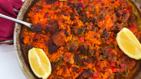 Traditional-Spanish-Paella-dish-with-chicken,-vegetables-and-lemon-slices-in-a-restaurant,-seafood-with-rice-in-Marbella-Spain,-4K-shot