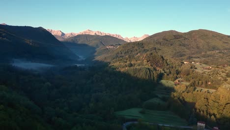 Vista-Aérea-De-Un-Bosque-Con-Niebla-A-La-Hora-Dorada-De-La-Mañana,-Colina-Y-Montaña-En-El-Fondo,-Toscana,-Italia,-Europa