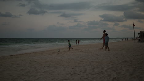 Dad-playing-football-soccer-with-his-kids-in-a-white-sand-beach-with-crystal-clear-ocean-in-Cancun,-Mexico