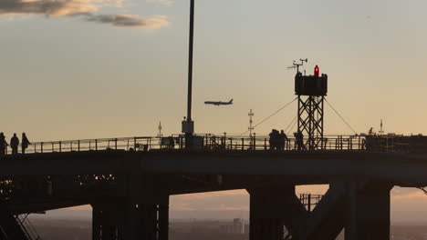 Tourist-Steht-Auf-Der-Hafenbrücke-In-Sydney,-Während-Sich-Ein-Flugzeug-Dem-Flughafen-Nähert