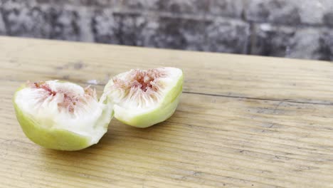 Fig-Splitted-in-Half-Over-A-Light-Brown-Table-With-Wall-In-The-Background