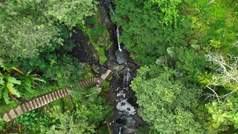 Group-of-People-Enjoy-Gembleng-Waterfall,-Bathing-Natural-Pools-in-Sidemen-Village-Jungle-Rainforest---Aerial-Top-Down