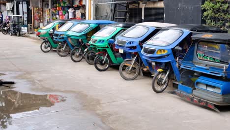 Row-of-cool,-funky-and-colourful-tricycle-taxi-automobiles-parked-up-and-waiting-for-tourist-on-the-streets-of-El-Nido-in-Palawan,-Philippines,-Southeast-Asia