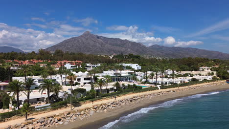 Aerial-view-of-Marbella-beach-and-apartments-with-a-mountain-view,-luxury-vacation-homes-in-Spain,-Malaga-holiday-destination,-4K-shot-moving-right