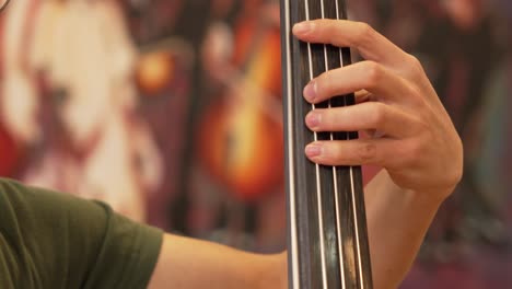 Man-Playing-Double-Bass-with-Left-Hand-Close-Up-Shot-in-a-Musical-Studio