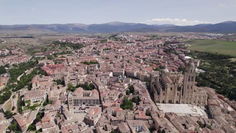 Aerial-pullback-view-over-Segovia,-Spain,-revealing-Gothic-style-cathedral