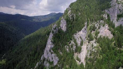 Drone-flying-in-between-giant-rocks-revealing-forest-mountain-landscape