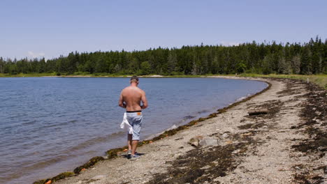 Adult,-white,-shirtless-male-walking-down-a-New-England-beach-in-late-summer