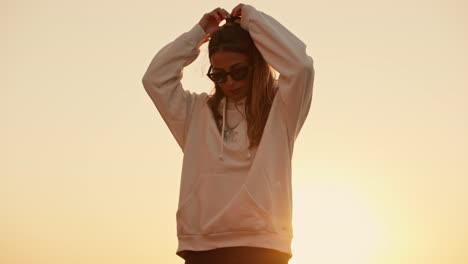 Slow-motion-tilting-shot-showing-a-beautiful-girl-fixing-her-hair-during-sunset