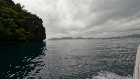 Island-hopping-boat-tour-with-scenic-view-of-tropical-island-and-cloudy,-overcast-and-dramatic-sky-during-monsoon-season-in-Palawan,-Philippines