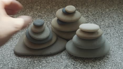Female-hands-stacking-pebbles-on-windowsill-in-apartment,-close-up